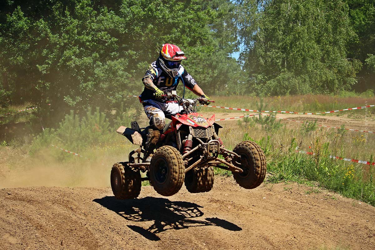 Un quadiste saute par-dessus une colline avec son quad