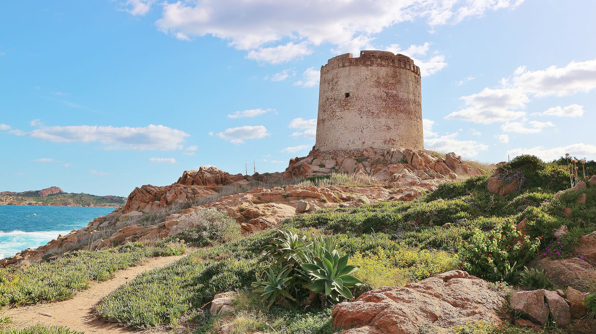 Les ruines d'une tour se dressent sur une colline et la mer est visible en arrière-plan