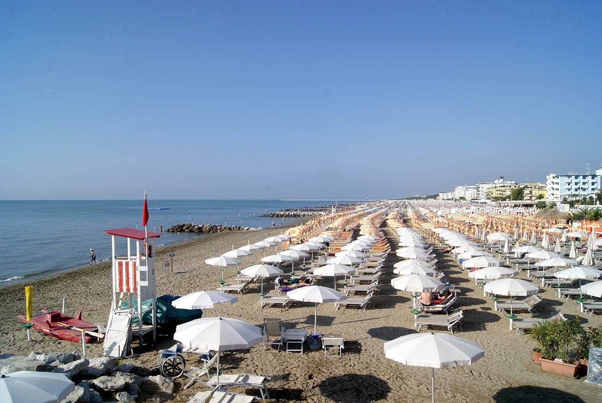 Parasols blancs tendus sur une plage de sable directement au bord de la mer bleue