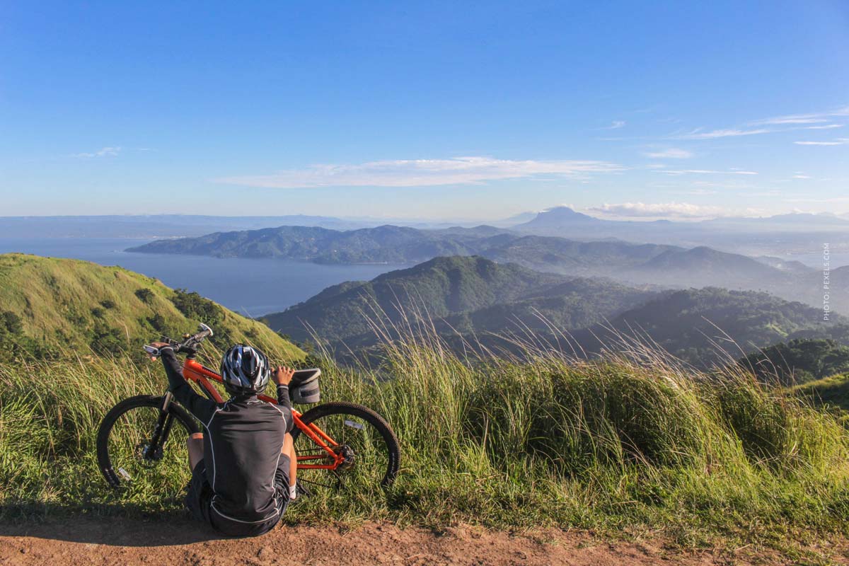 Une personne est assise devant son vélo et les montagnes sont visibles en arrière-plan.
