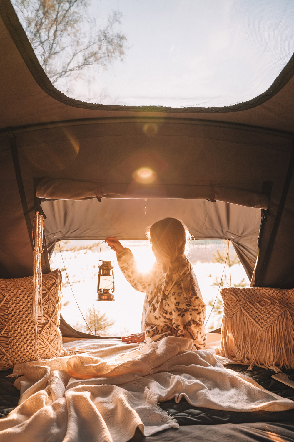 Une femme regarde le crépuscule depuis l'ouverture de sa tente de toit