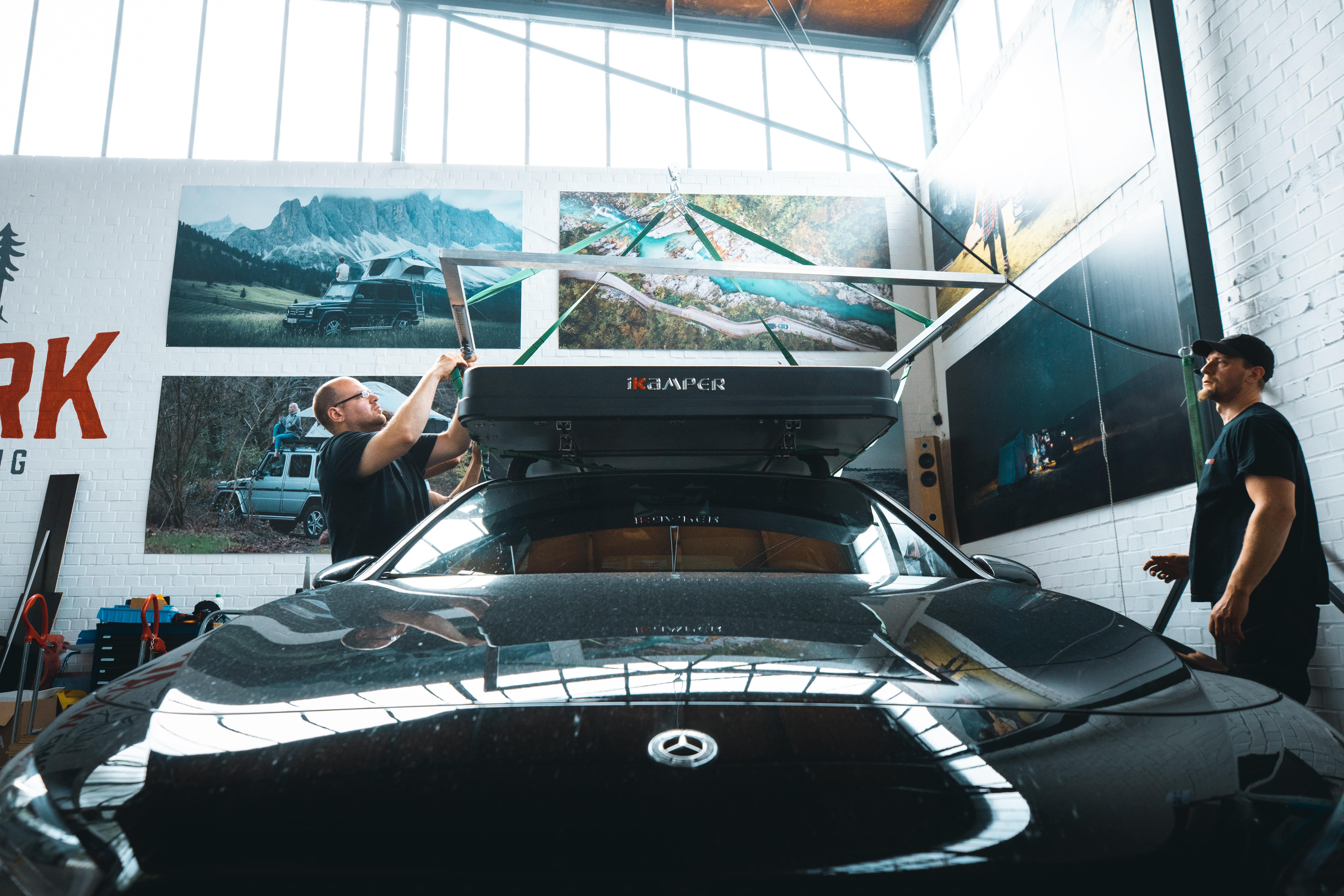 Des employés de CAMPWERK montent une tente de toit sur une voiture noire