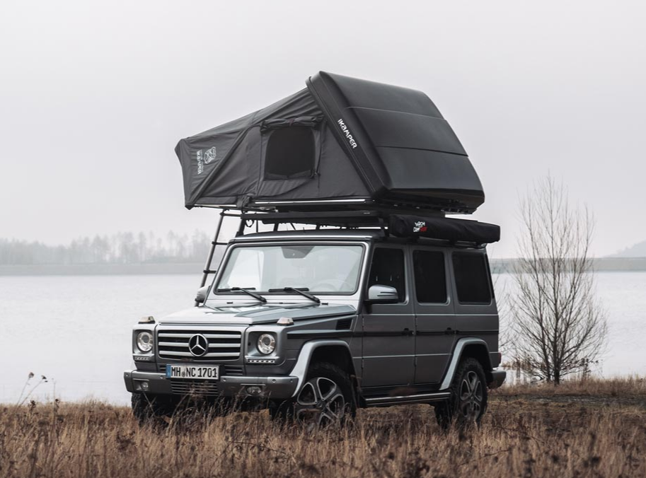 Tente de toit Skycamp sur une Mercedes gris foncé au bord d'un lac