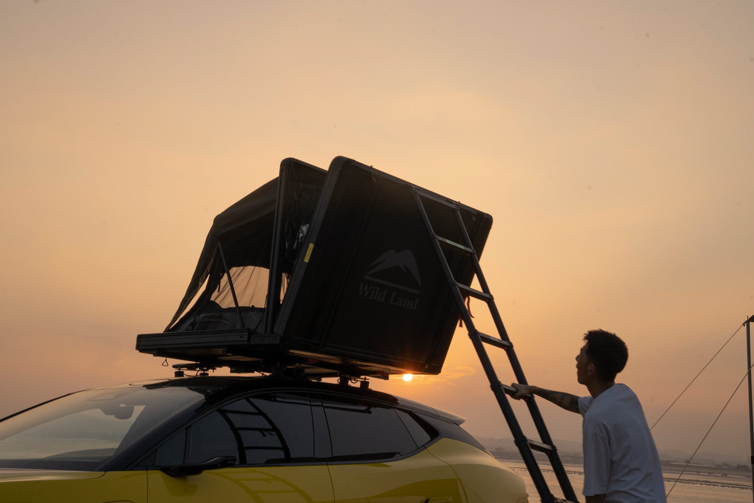 Un campeur grimpe dans sa tente de toit