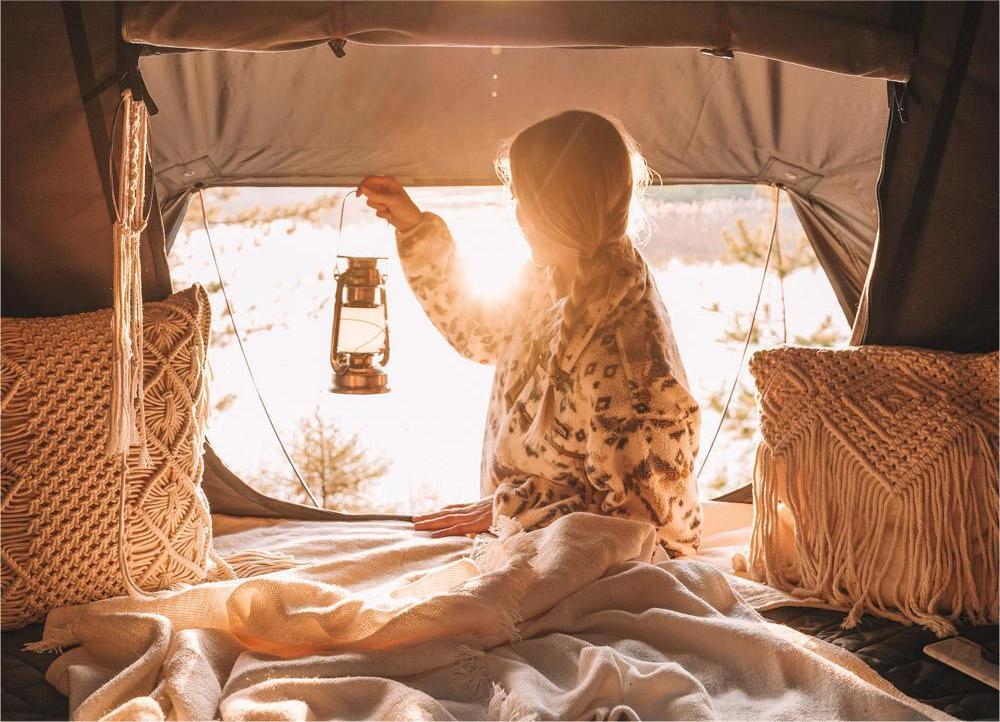 Une femme regarde le crépuscule depuis l'ouverture de sa tente de toit